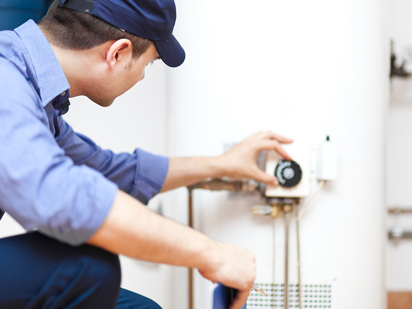Tech adjusting a dial on a water heater