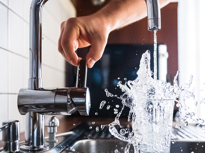 Running tap water in to a glass in the sink